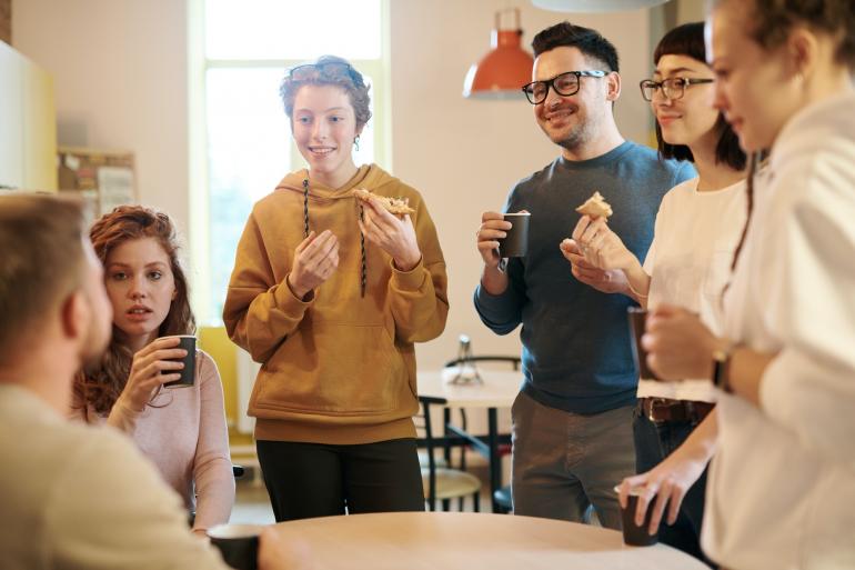 Foto: Fauxels / Pexels.com Gruppe Menschen steht in Kaffeeküche zusammen und unterhält sich.